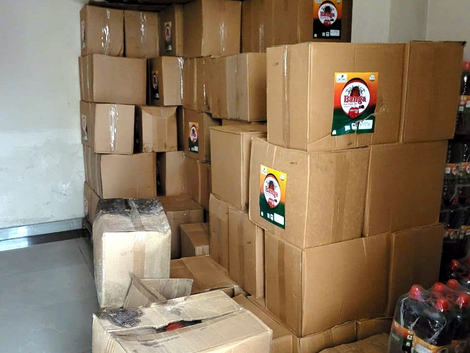 Stacked cartons of Okomu Banga Red Palm Oil alongside bottled stock
